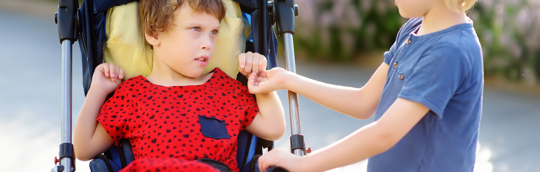 A woman with a boy and a disabled girl in a wheelchair walking i